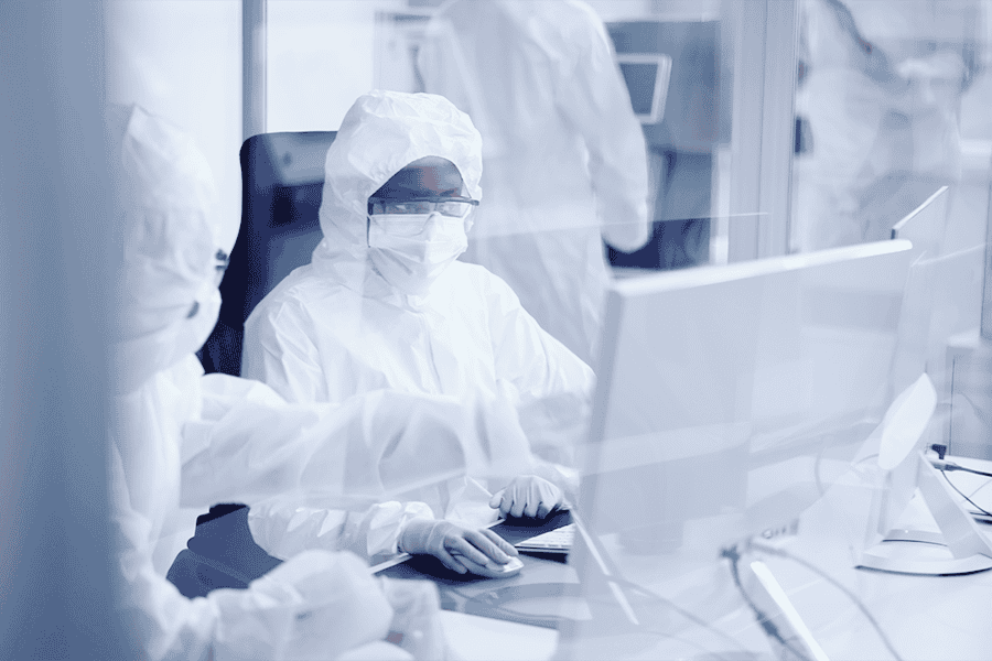 Cleanroom technicians working at a computer station to monitor and manage laboratory processes.